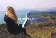 Moça sentada em um penhasco olhando para uma estrada à beira-mar em um momento de fé e reflexão em tempos de crise