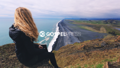 Moça sentada em um penhasco olhando para uma estrada à beira-mar em um momento de fé e reflexão em tempos de crise