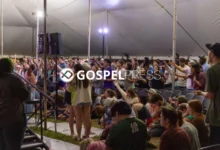 Jovens com as mãos levantadas em adoração durante um avivamento em tenda no campus de uma universidade do Texas, sob iluminação dramática.